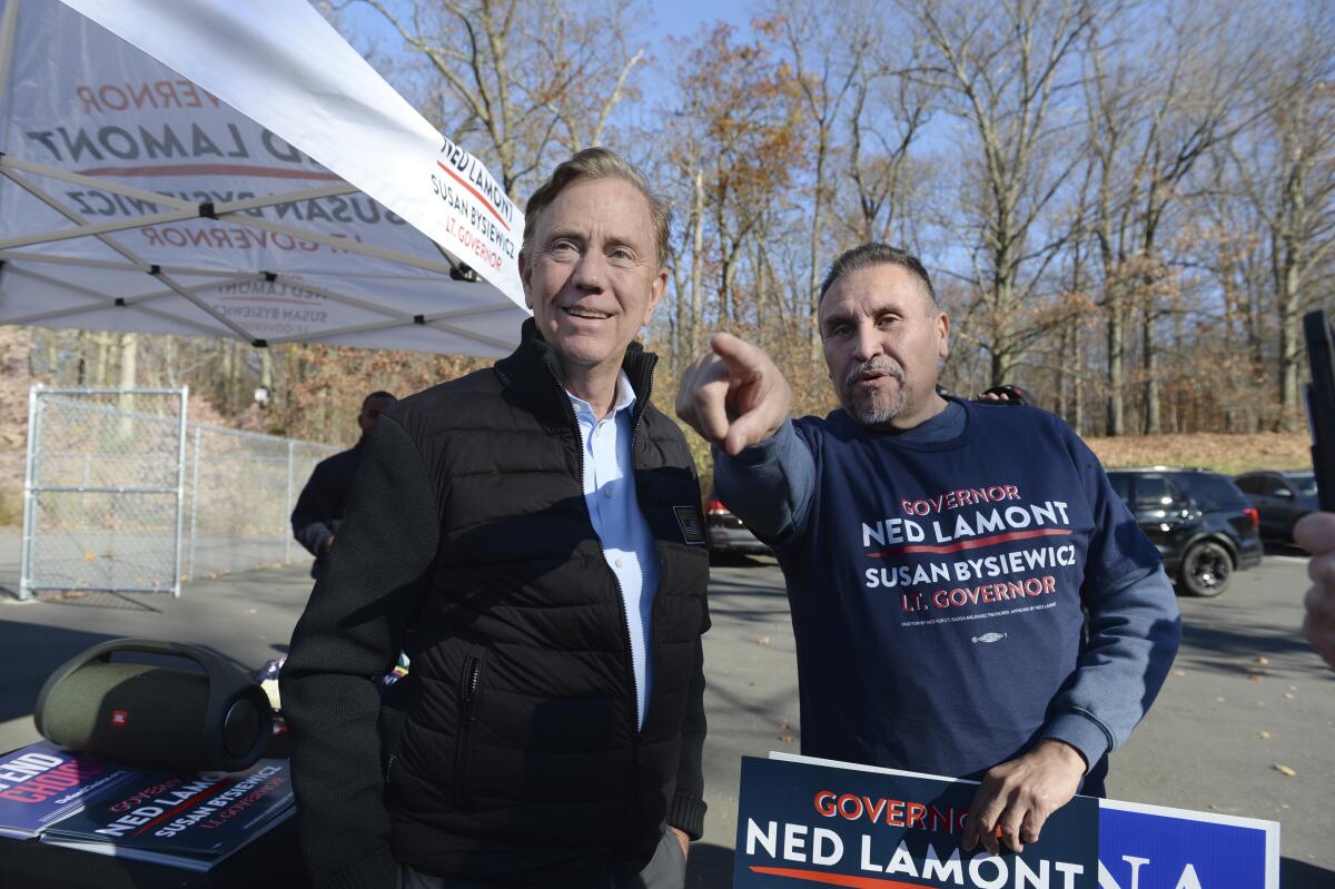 Connecticut Gov. Ned Lamont, left, talks with state Rep. Bobby Sanchez while making a campaign stop at the Pulaski Middle School polling place in New Britain, Conn., on Election Day, Tuesday, Nov. 8, 2022. (Cloe Poisson/Hartford Courant via AP)