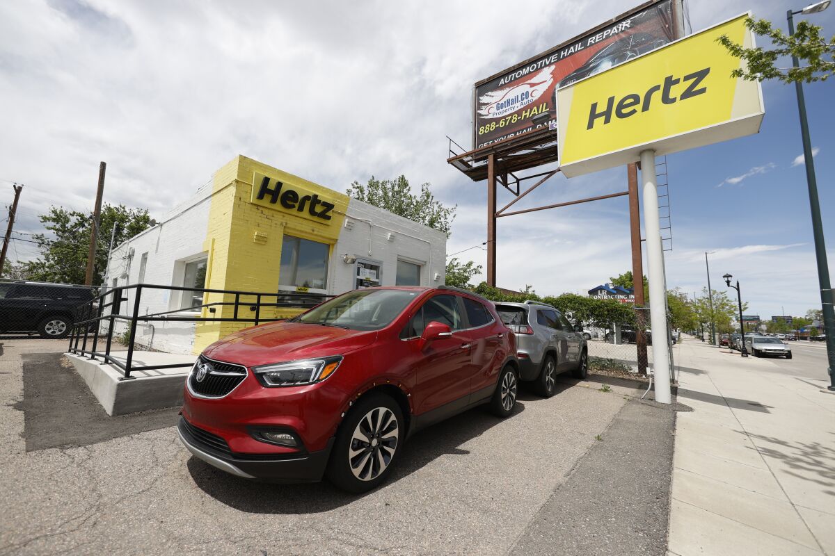 This May 23, 2020, photo shows rental vehicles parked outside a closed Hertz car rental office in south Denver. Hertz says it will pay approximately $168 million by the end of the year to settle the majority of the lawsuits brought against the rental car company by some of its customers who were wrongly accused of stealing cars they had rented. In April Hertz CEO Stephen Scherr, who took over the role in February, said that he was working to fix a glitch in the company’s systems that led to the incidents. (AP Photo/David Zalubowski, file)