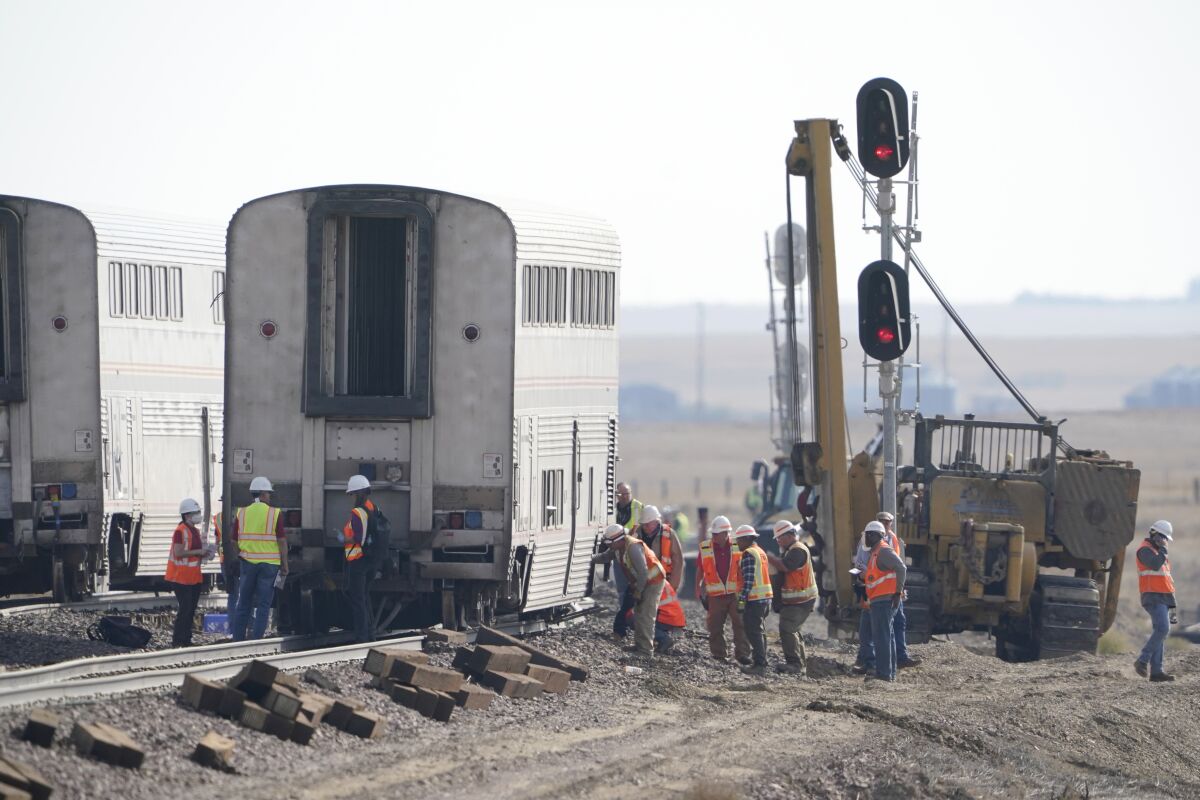 Workers examine a derailed Amtrak train car