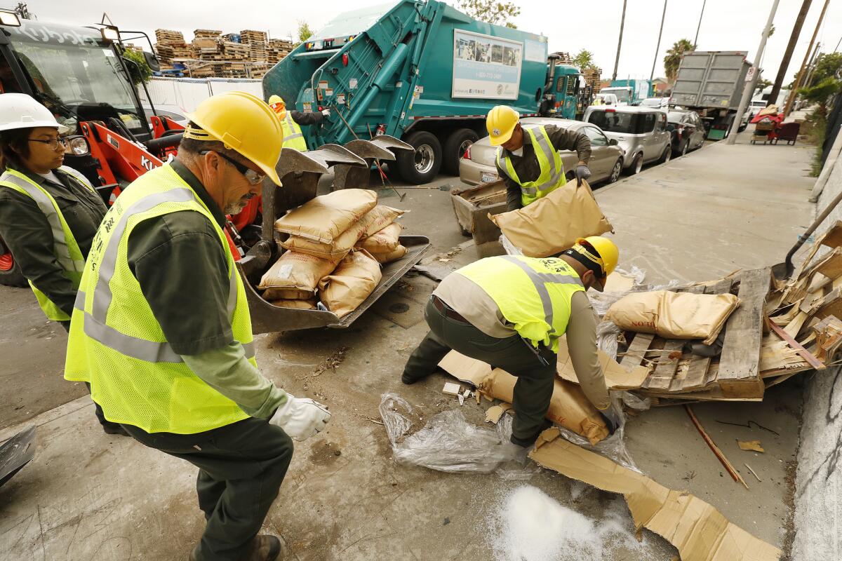 City of Los Angeles Bureau of Sanitation crews clean up items dumped on the street near the homeless encampment of Rickey Harris at 41st Place and Alameda Street.