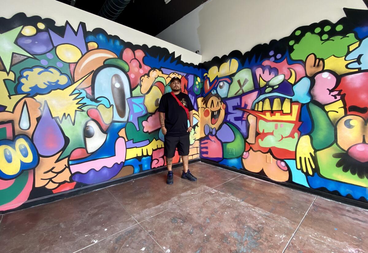 Juan Carlos Galindo poses next to his mural in the Front Gallery