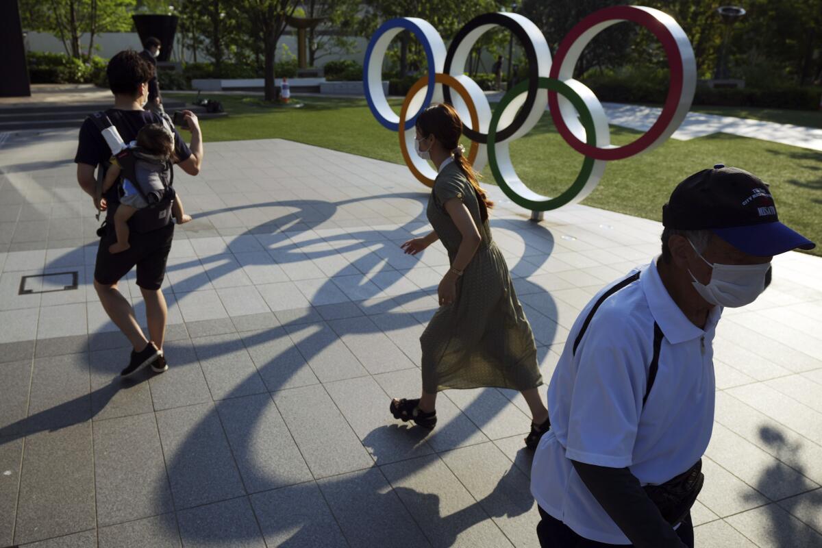 Transeúntes pasan frente a los anillos olímpicos en Tokio el 9 de junio del 2021. 