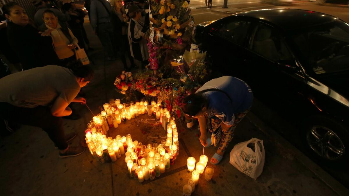 Women light votive candles at a sidewalk memorial for victims of a collision between a tour bus and a big rig that killed 13 people and injured 31 others near Palm Springs.