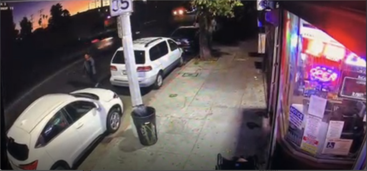 An image from surveillance camera video shows a man walking in the road next to parked cars