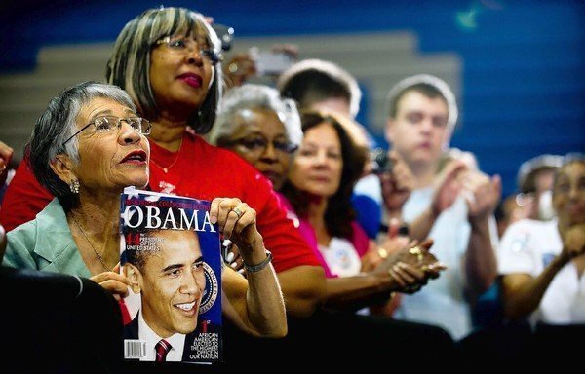 Maria Gray, left, holds up a magazine as President Obama speaks during a campaign event at Canyon Springs High School in Las Vegas.