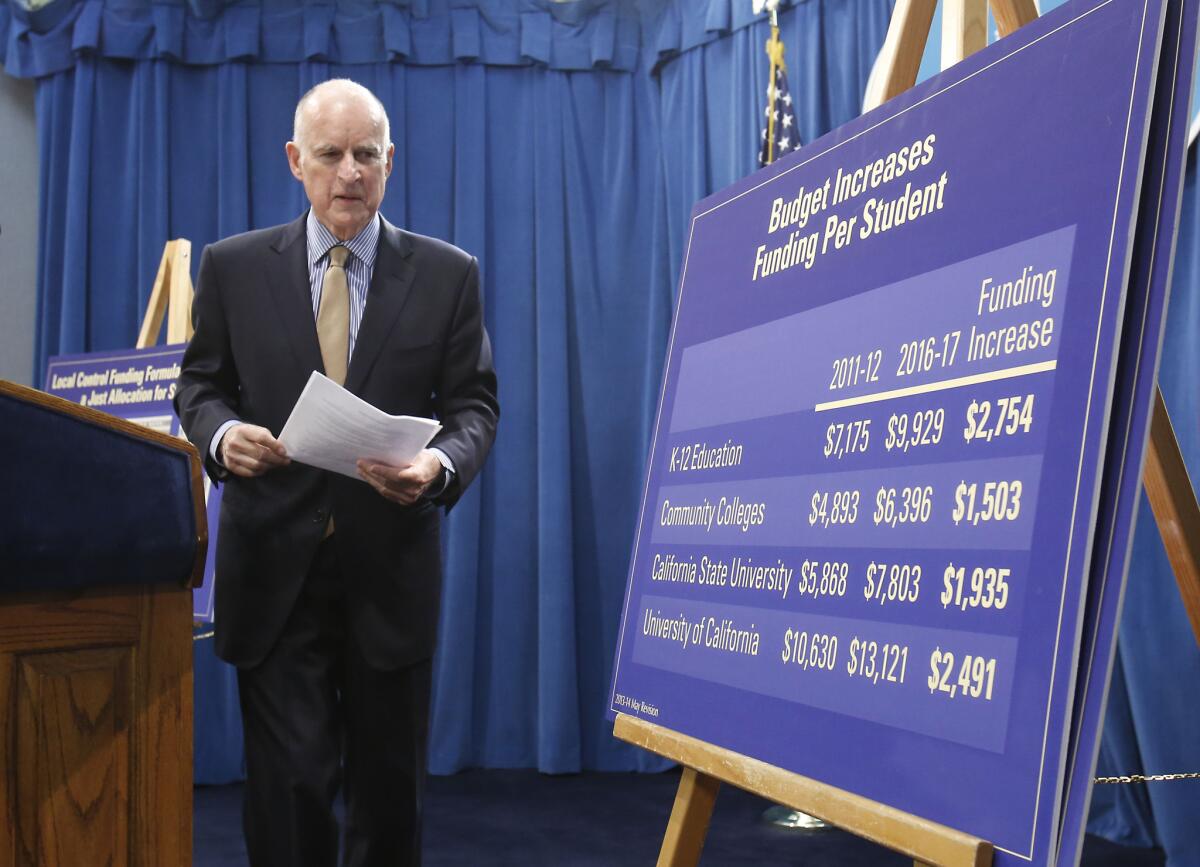 Gov. Jerry Brown walks past an education funding chart after presenting his revised 2013-14 state budget plan at the Capitol in Sacramento on Tuesday.