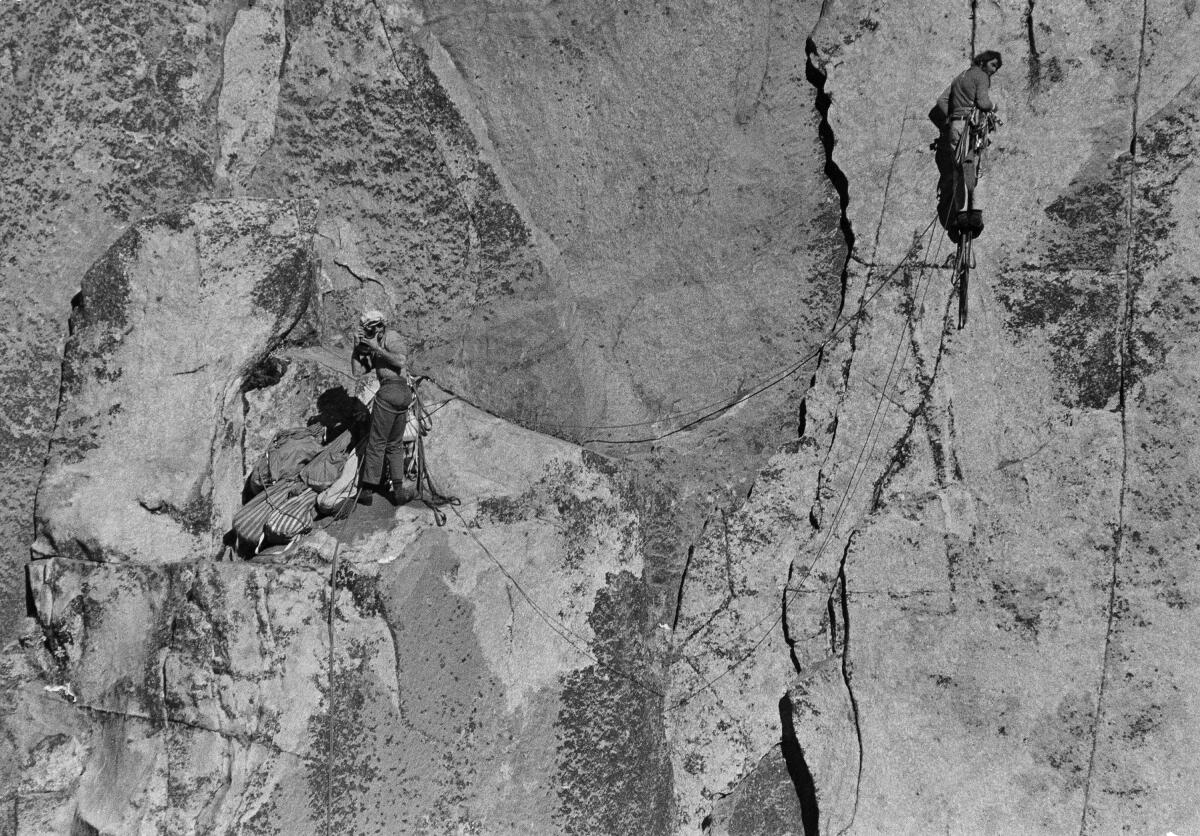 Two men are shown on a sheer rock face with climbing ropes.