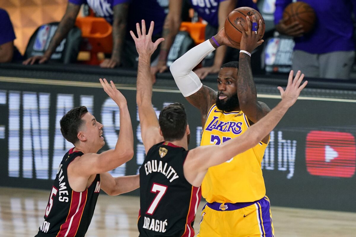 Lakers forward LeBron James looks to pass while covered by Miami's Duncan Robinson and Goran Dragic during Game 1.