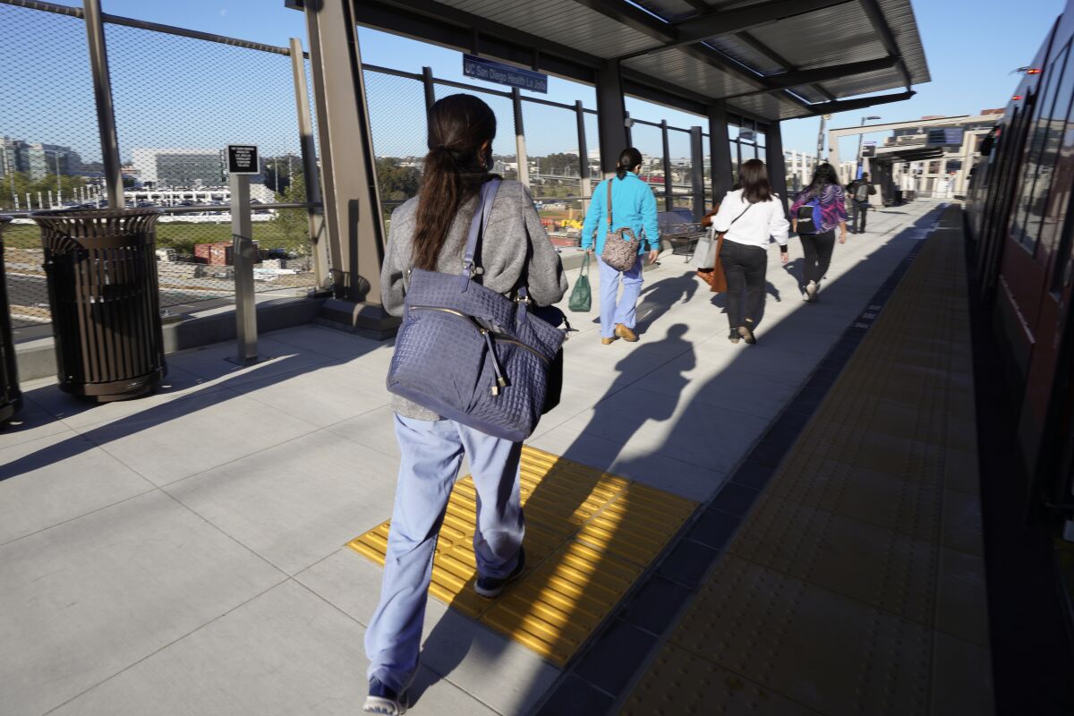 Riders exit a San Diego trolley Blue Line train at the UC San Diego Health station in La Jolla.