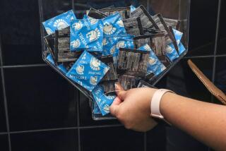 Calexico, CA - May 26: Frida Diaz, 21, a member of Planned Parenthood Generation Action (PPGA), restocks condom dispenser in a restroom of Associated Students Union building at San Diego State University, Imperial Valley Campus on Thursday, May 26, 2022 in Calexico, CA. (Irfan Khan / Los Angeles Times)