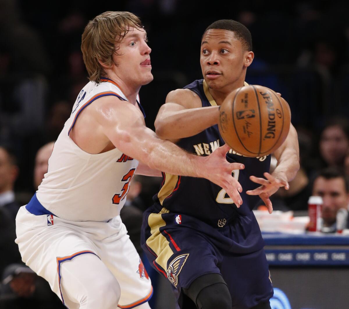 El escolta de los Pelicans de Nueva Orleans, Tim Frazier, pasa ante la defensa del jugador de los Knicks de Nueva York, Ron Baker.