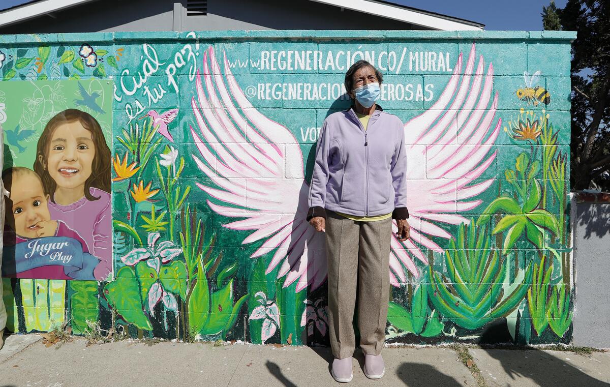 Local resident Cristina Prada stands amid "peace" wings during an October 2020 mural dedication in Costa Mesa.