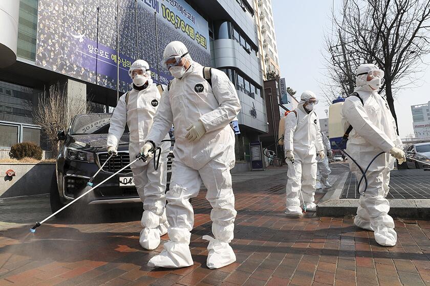 Workers spray disinfectant in front of a church in Daegu, South Korea, on Thursday.