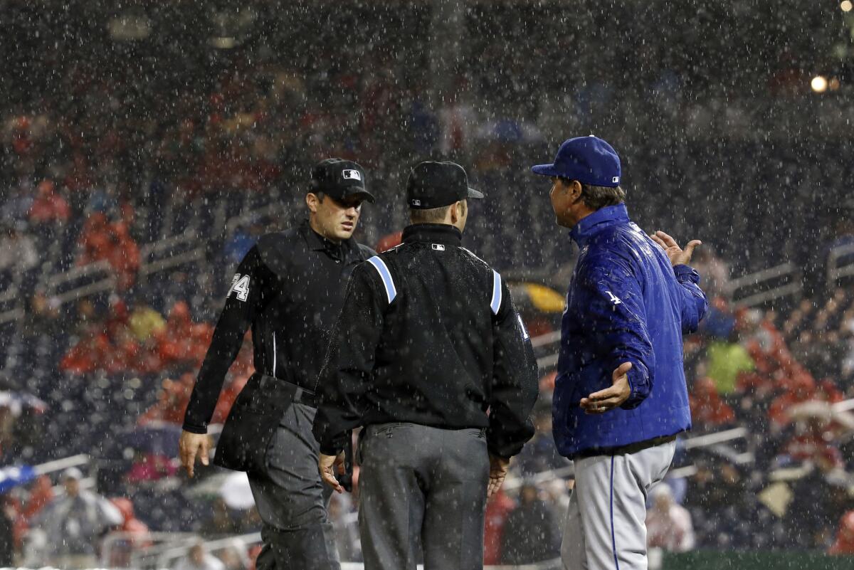 Umpires John Tumpane, left, and Mark Wegner listen to Dodgers Manager Don Mattingly as they discuss a rain delay in the fourth inning in Washington.