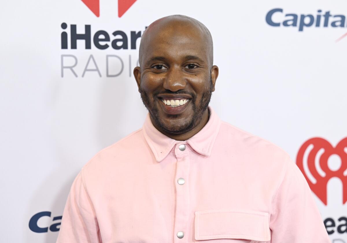 A bald man smiling in a pink button-up shirt