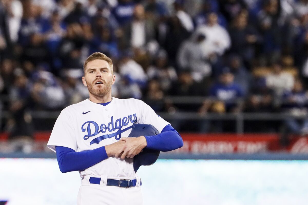 Dodgers first baseman Freddie Freeman holds his helmet and looks at the crowd