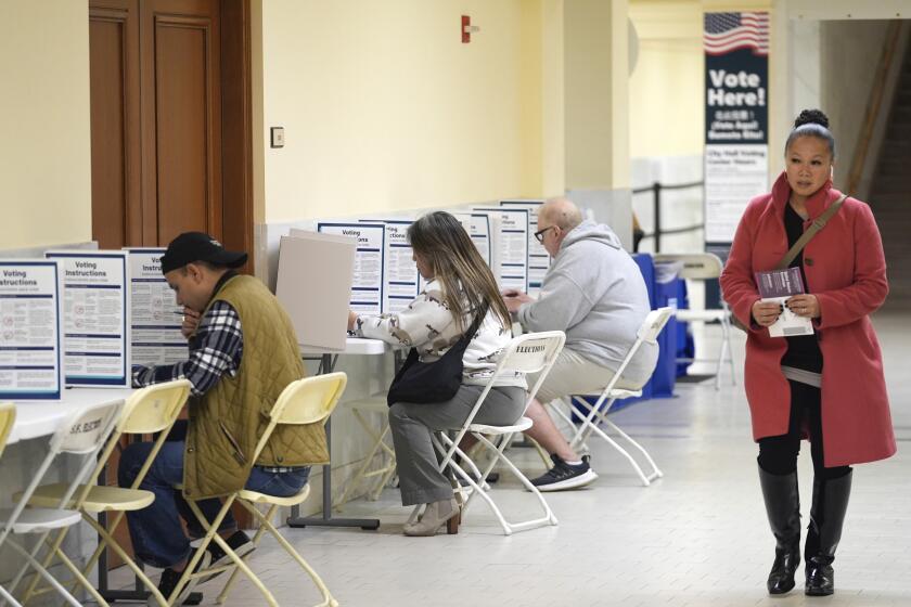 FILE - A woman walks with her ballot to a vacant voting booth at City Hall in San Francisco, March 5, 2024. (AP Photo/Eric Risberg, File)