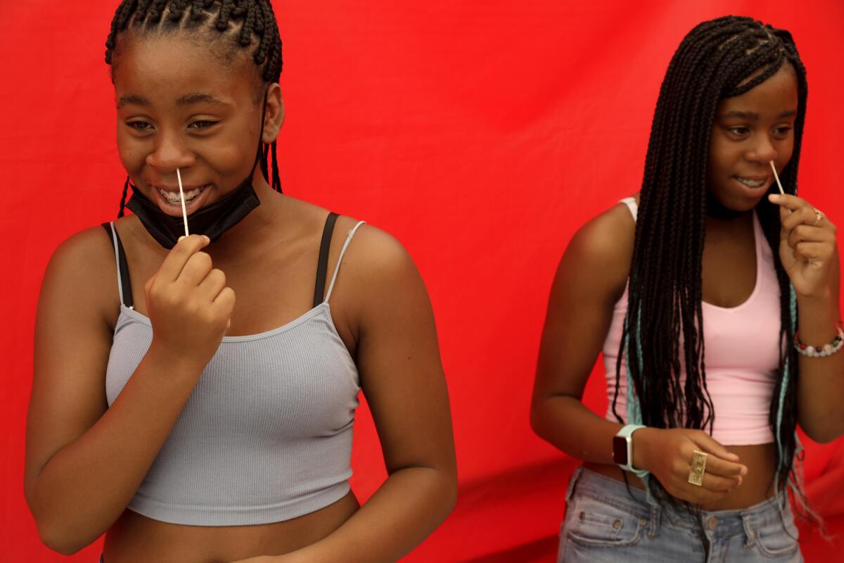 Twins Aniyah Kelly and her sister Amiyah, both 15, insert swabs in their noses to test themselves for COVID-19.