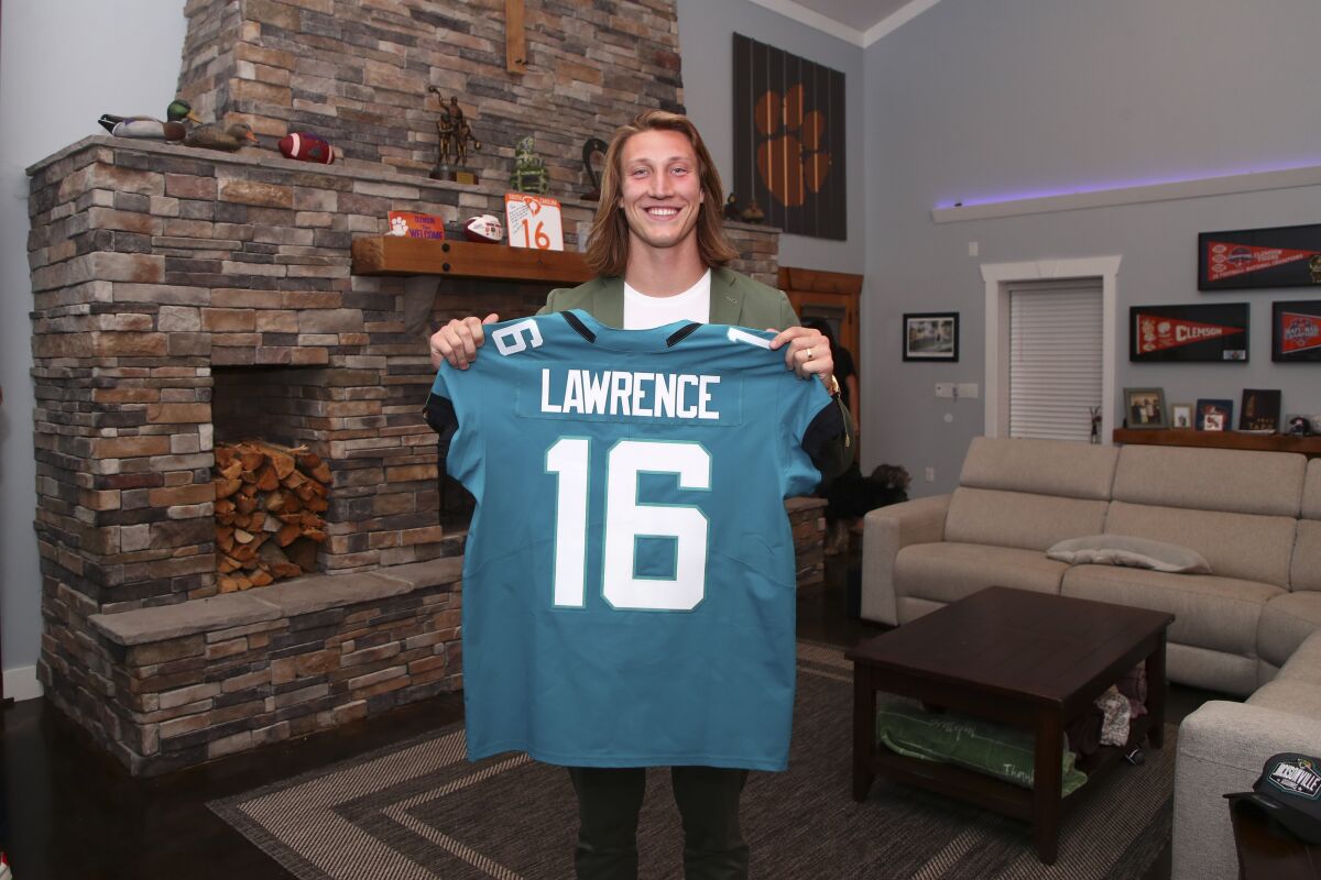 Clemson quarterback Trevor Lawrence holds up a jersey after being selected No. 1 by the Jacksonville Jaguars on Thursday.