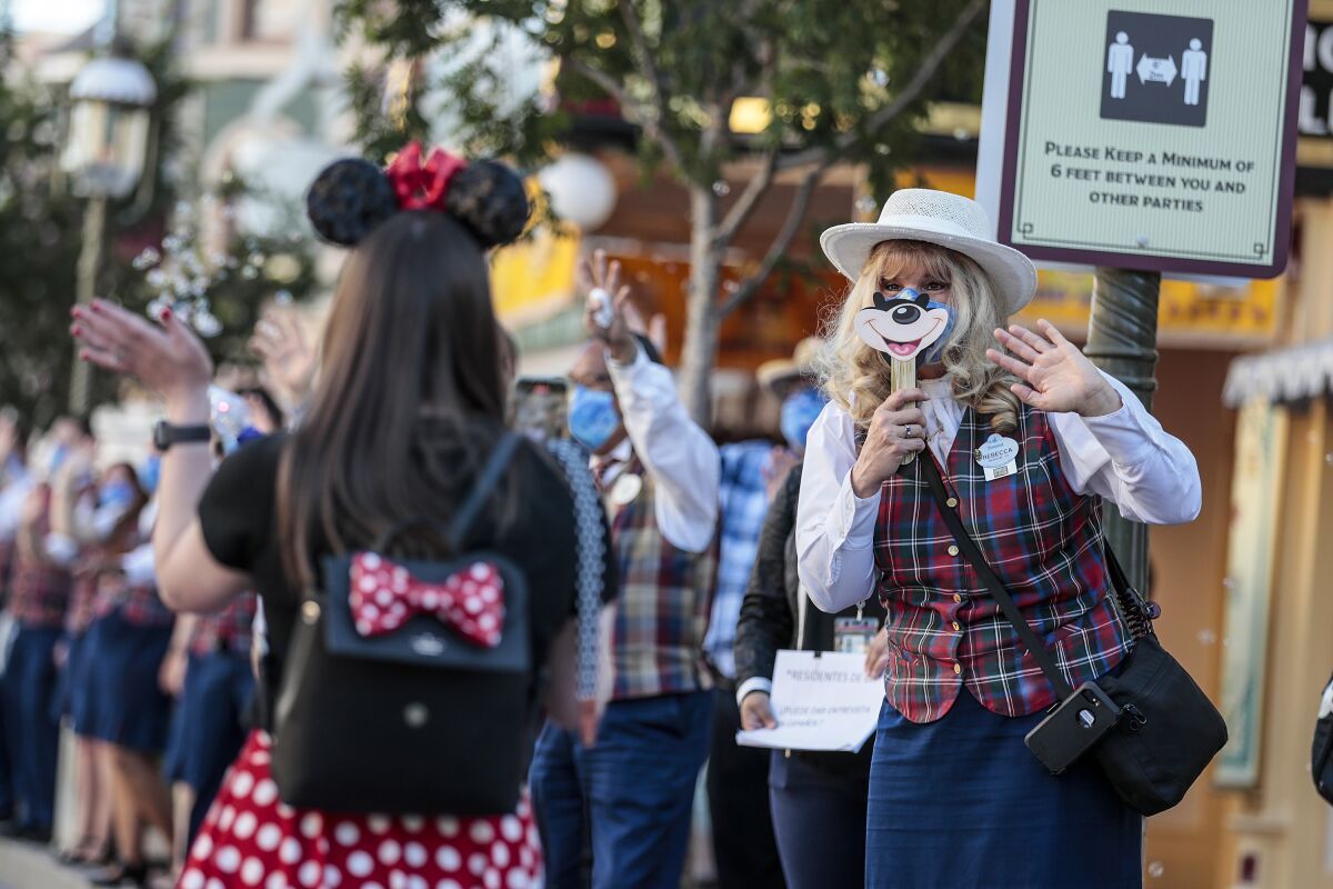 Cast members greet visitors inside Disneyland as the theme park reopens.