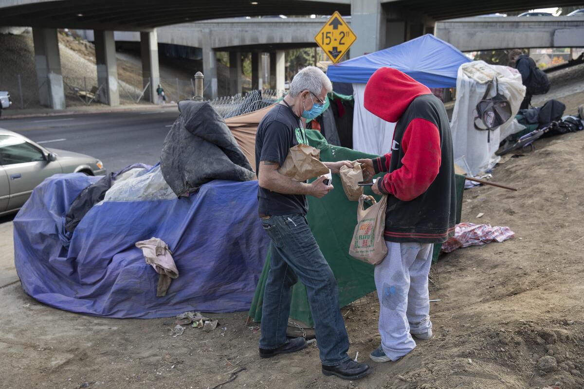 Homeless man receives care package containing food, hygiene products at a homeless encampment near the 101 freeway