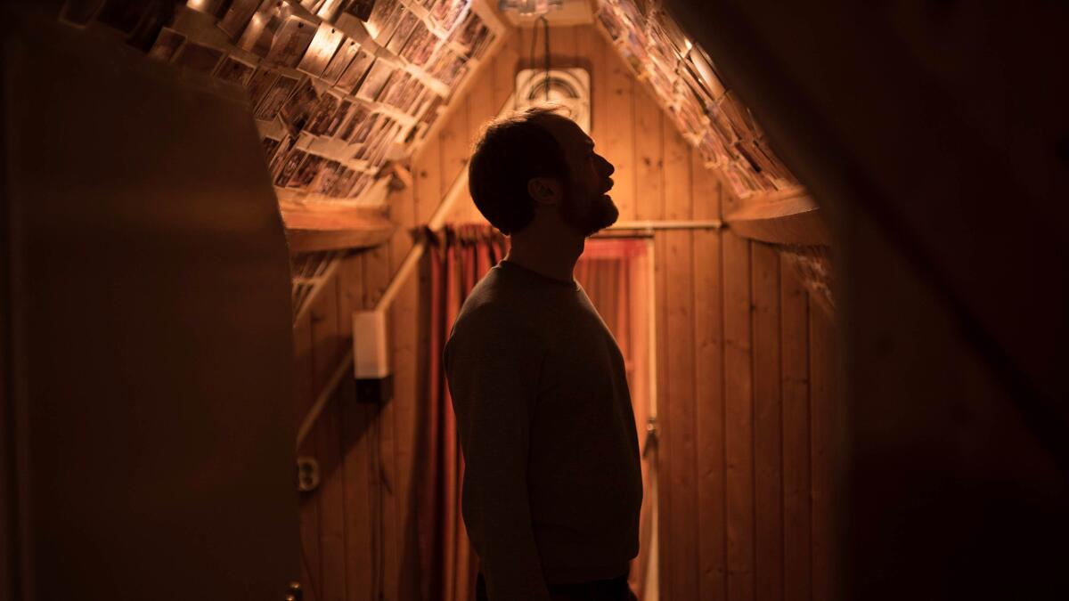 The silhouette of a man looking at photos on the wall 