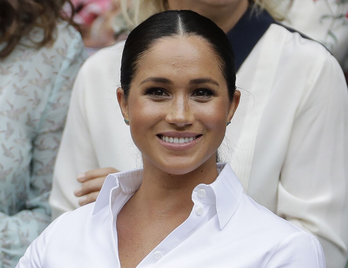 A smiling woman wearing a white blouse who has her hair pulled back.