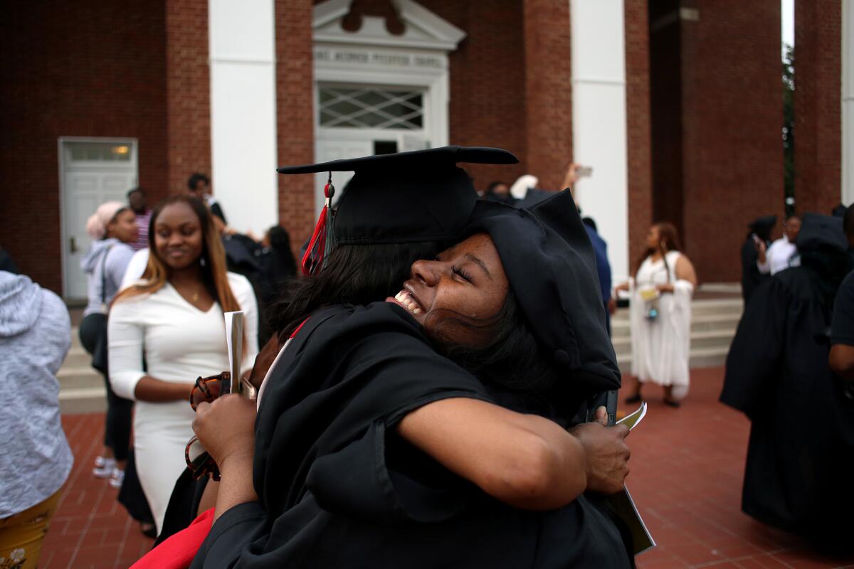 Bennett College senior Brie'Asha Nwanze embraces a classmate outside the campus chapel after a ceremony where they received their caps and gowns.