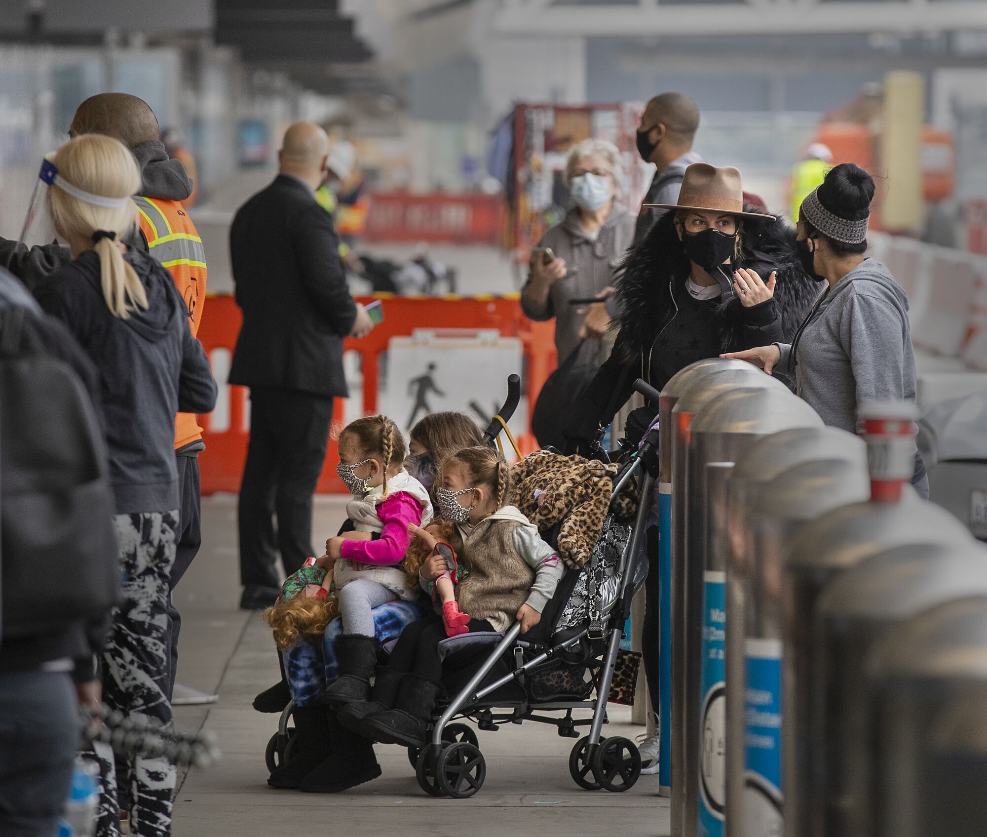 Travelers wearing face coverings arrive at Los Angeles International Airport.