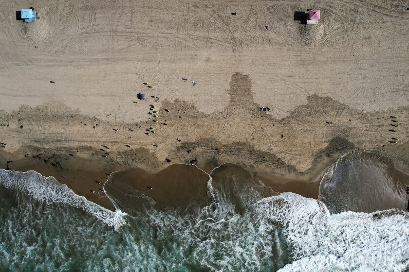 FILE - In this aerial photo taken with a drone, workers in protective suits continue to clean an oil-contaminated beach in Huntington Beach, Calif., Oct. 11, 2021. According to a federal report released Wednesday, Sept. 28, 2022, oil and natural gas spills from tanker ships and pipelines in U.S. waters dropped dramatically from the last decade of the 1990s to the one from 2010 through 2019. (AP Photo/Ringo H.W. Chiu, File)