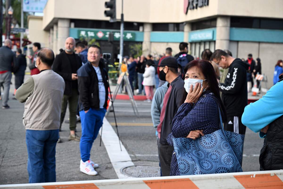 People stand in the street near barriers in Monterey Park.