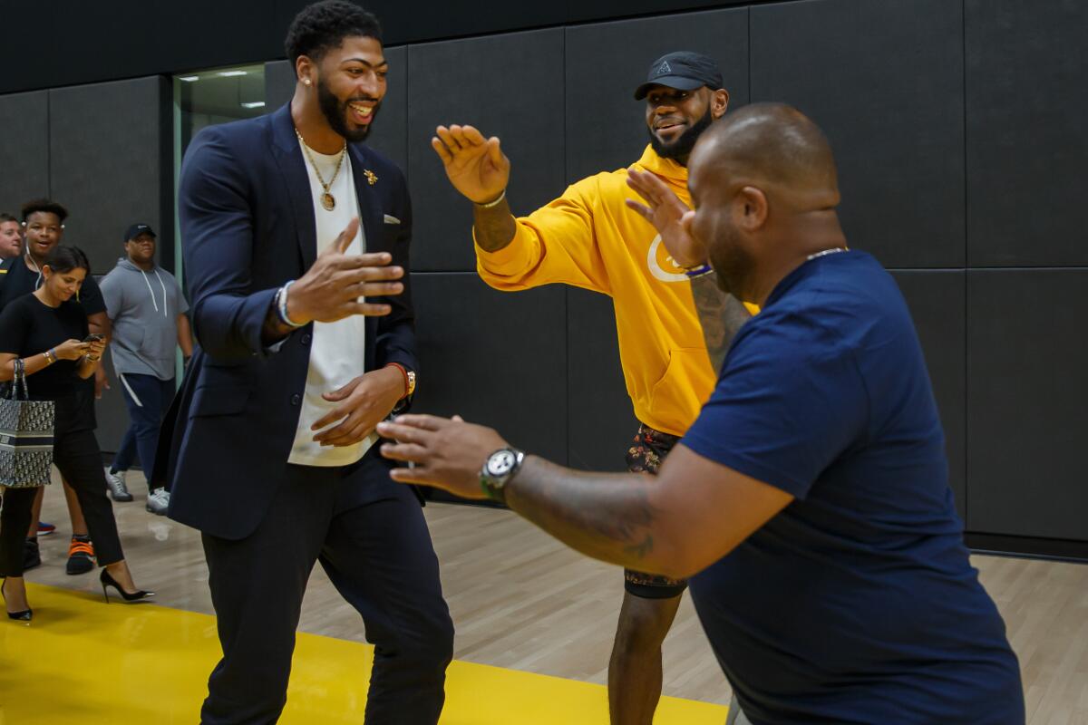 Anthony Davis greets  fellow teammate LeBron James and LeBron's friend, Randy Mims, after Davis' press conference at the UCLA Health Training Center in El Segundo.