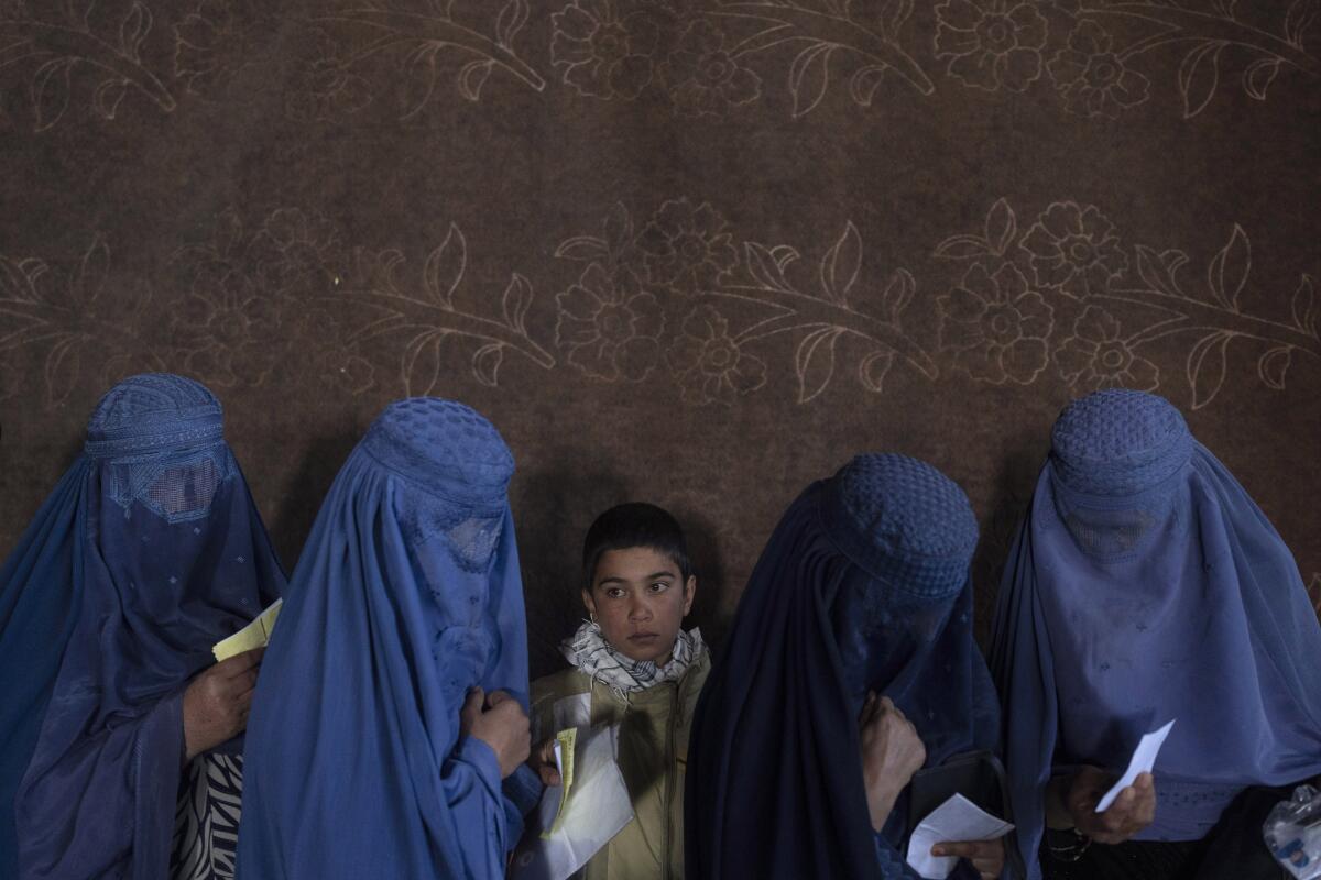 Afghan women wearing veils stand in line.