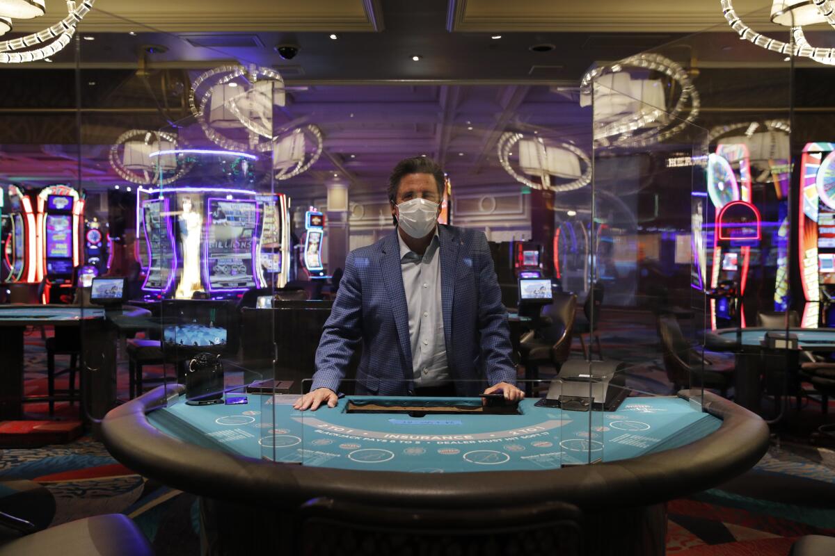 Bill Hornbuckle of MGM Resorts International stands behind a see-through barrier at a blackjack table in the Bellagio casino.
