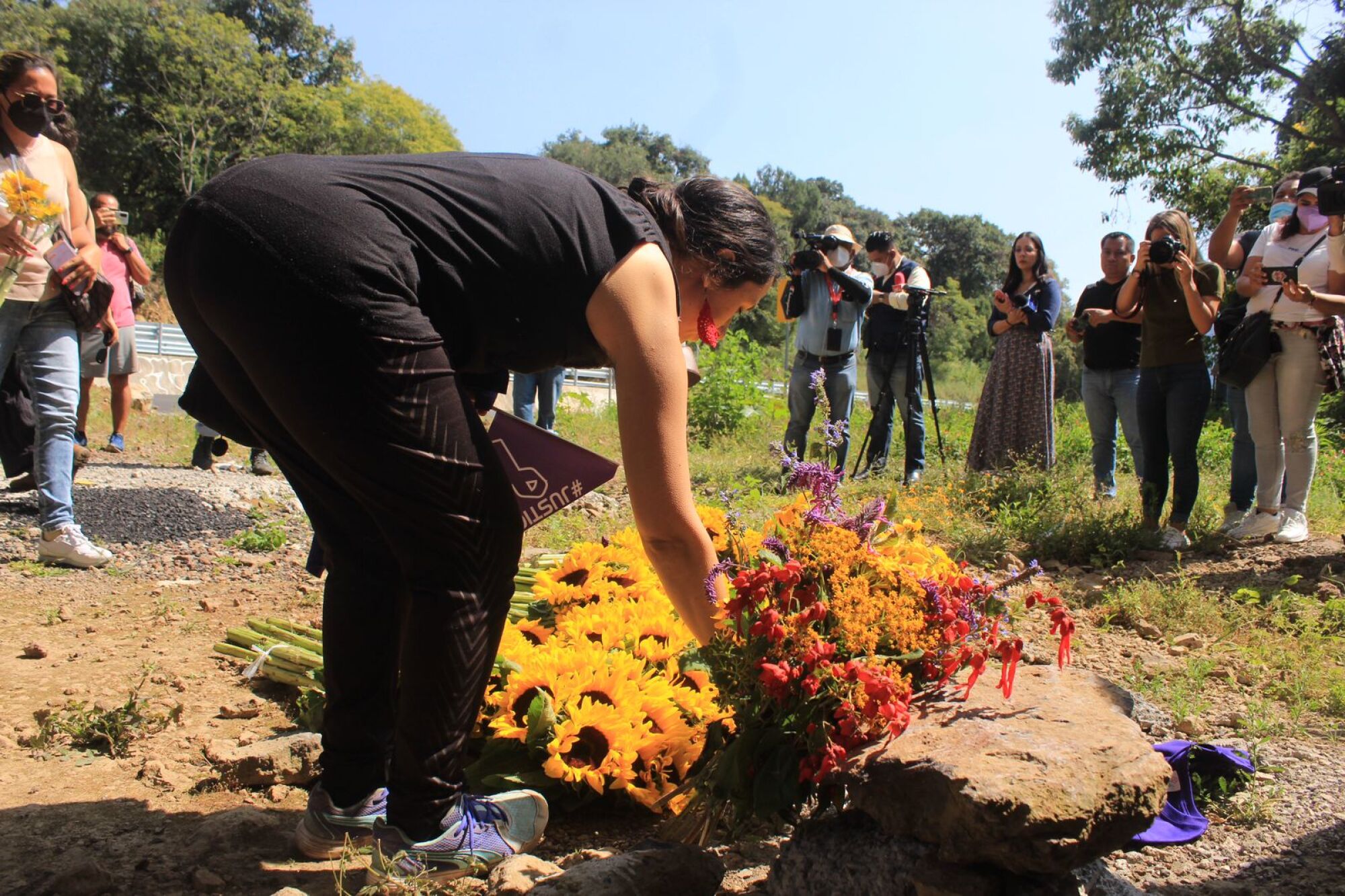 Mourners place sunflowers at a spot along the highway where the body of Ariadna López was found.
