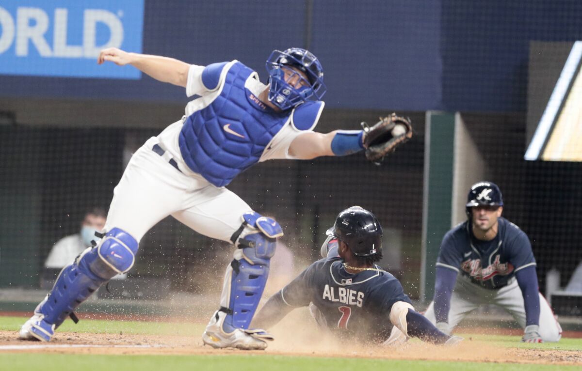 Atlanta Braves' Ozzie Albies scores under Dodgers catcher Will Smith during the fourth inning in Game 7 of the NLCS.