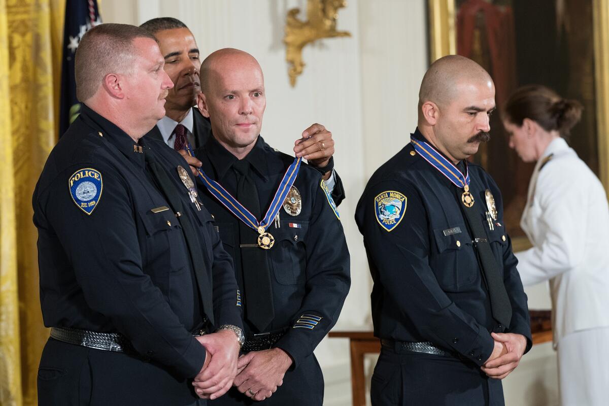 Flanked by Santa Monica College Police Department Capt. Raymond Bottenfield, left, and Officer Jason Salas, right, President Obama presents Officer Robert Sparks, center, with the Medal of Valor during a ceremony at the White House on May 16, 2016.