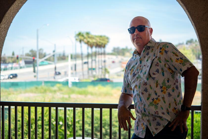 Isa Bahu leans against a railing overlooking a vacant lot in Anaheim.