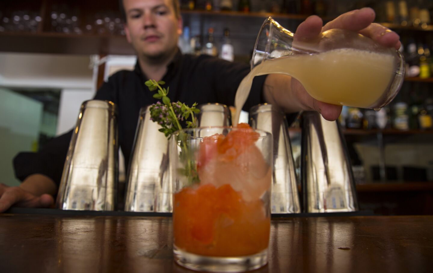Bartender Andrew Wilcox mixes an El Paseo with tequila, mezcal, strawberry liquor, ginger, lime, thyme and strawberry shrub granita at Michael's.