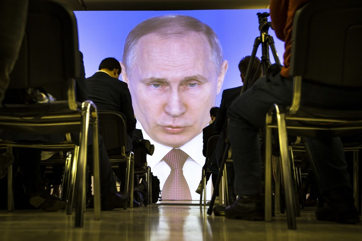 Journalists watch as Russian President Vladimir Putin gives his annual state of the nation address in Moscow on March 1.