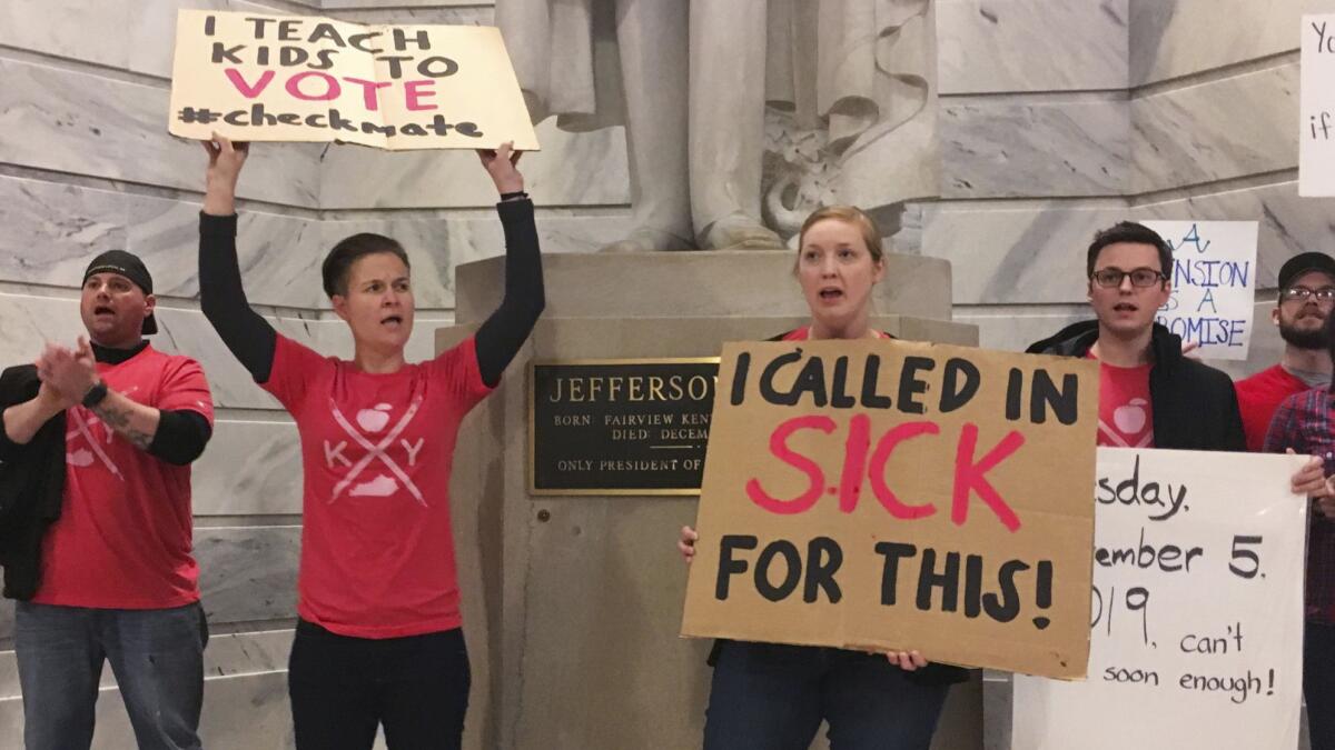 Whitney Walker, second from left, and Tracy Kurzendoerfer, third from left, protest outside of Kentucky Gov. Matt Bevin's office on Friday. Both called in sick to protest a bill lawmakers passed late Thursday that makes changes to the state's pension system.