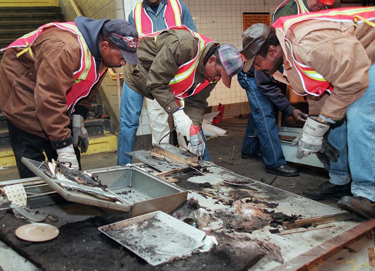 Workers bend over a charred surface.