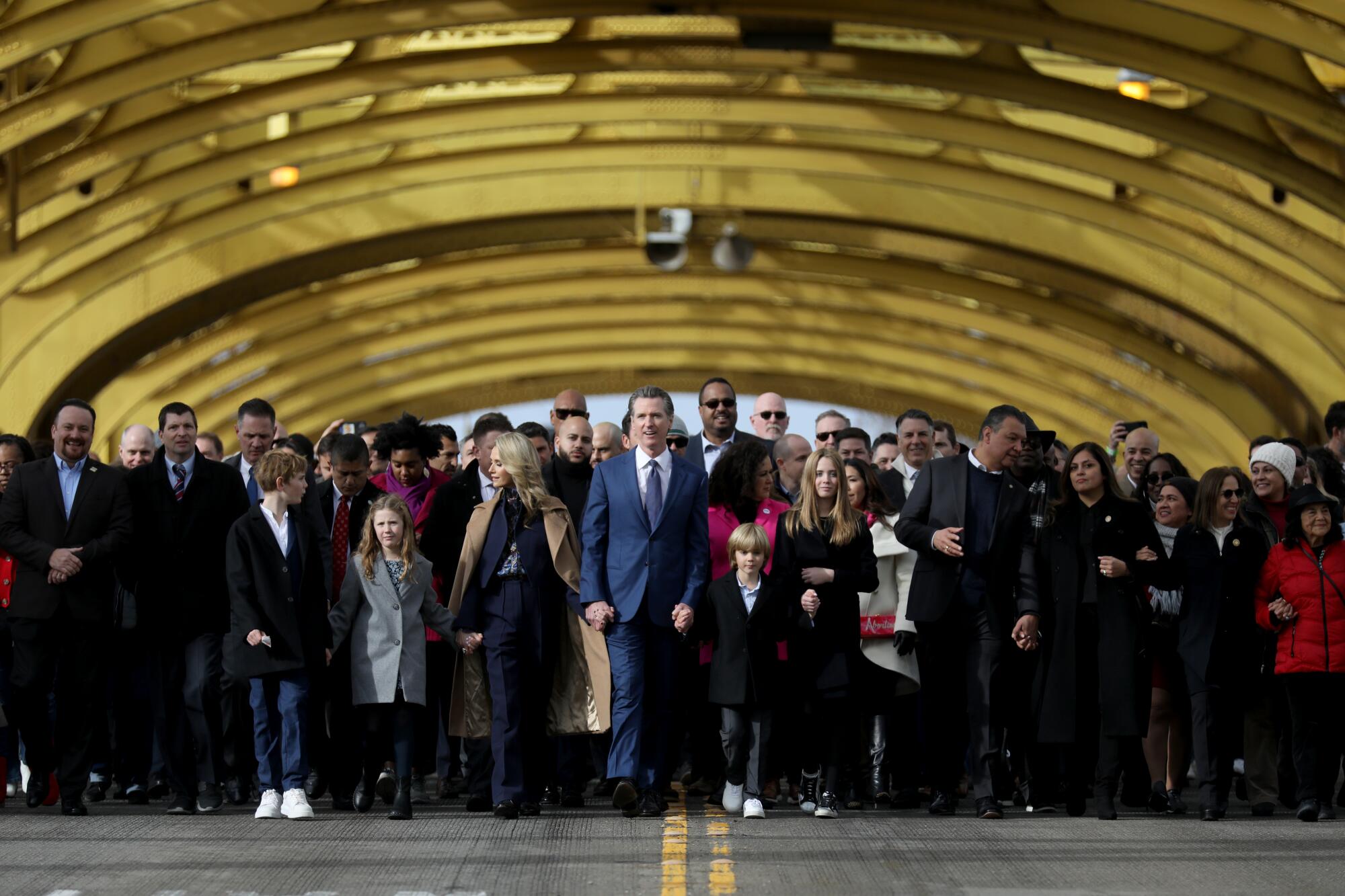 Gov. Gavin Newsom walks ahead of a crowd of people.