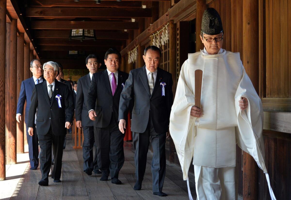 Japanese lawmakers follow a Shinto priest during a visit to the controversial Yasukuni shrine in Tokyo on Tuesday to honor the country's war dead.