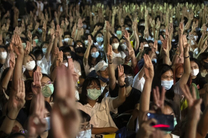 Pro-democracy students raise a three-finger salute, a resistance symbol borrowed by Thailand's anti-coup movement from the Hollywood movie "The Hunger Games," during a protest at Thammasat University in Pathum Thani, north of Bangkok, Thailand, Monday, Aug, 10, 2020. Protesters warned that they'll step up pressure on the government if it failed to meet their demands, which include dissolving the parliament, holding new elections and changing the constitution. (AP Photo/Sakchai Lalit)