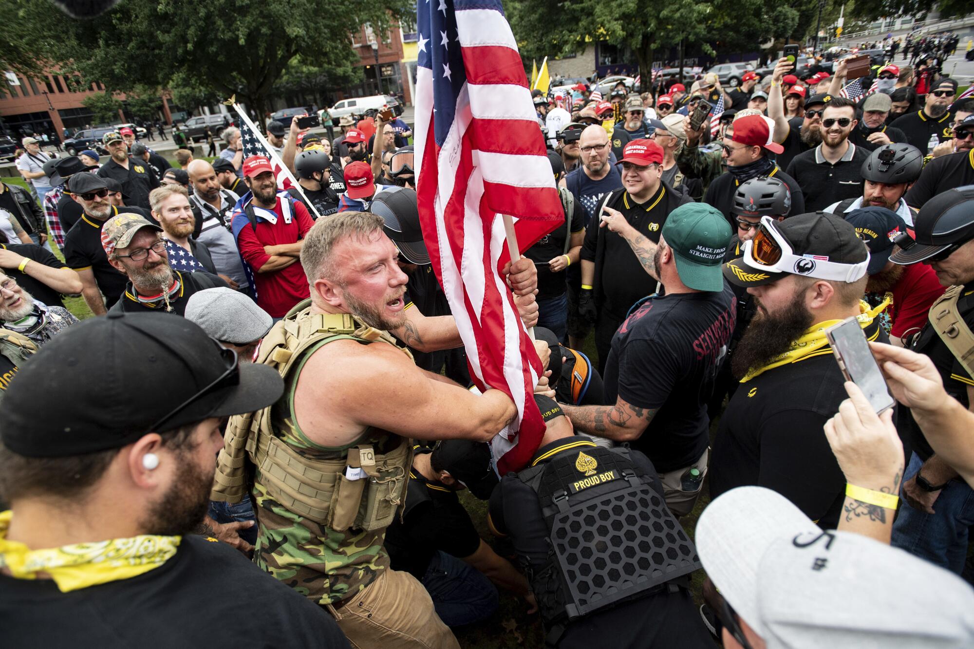Proud Boys demonstrators in tactical vests plant a U.S. flag in a park