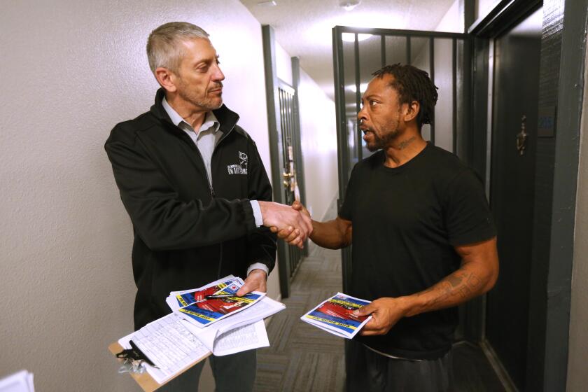 LOS ANGELES, CA - NOVEMBER 21, 2023 - Union leader Cliff Smith, left, shakes hands with Charles Jones after receiving his signature of support to become eligible to run for Los Angeles City Council in District 8 at the Robert Farrell Apartments in Los Angeles on November 21, 2023. To get on the ballot Smith must turn in 500 valid voter signatures from within the 8th District, which takes in part of South L.A. He tried in 2020 and fell short by a few dozen signatures. (Genaro Molina / Los Angeles Times)