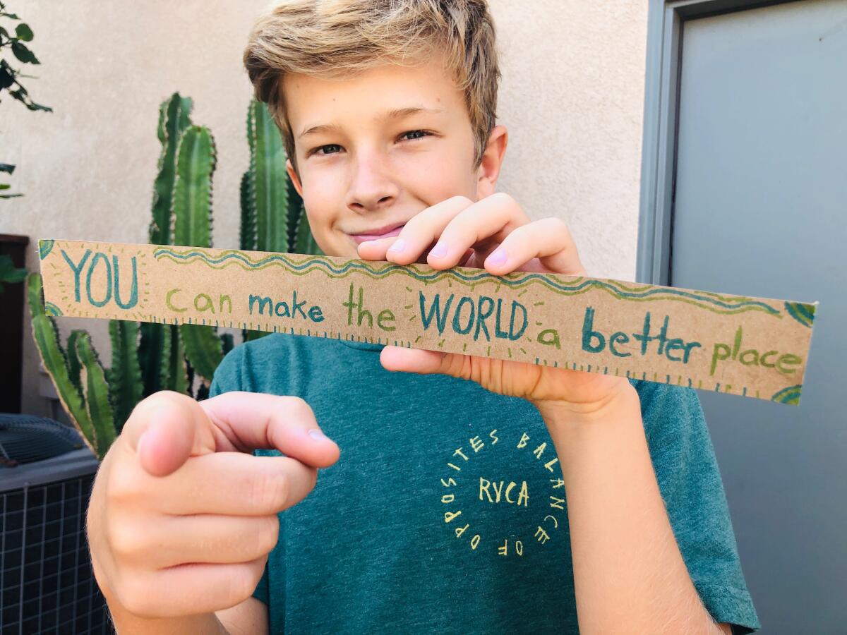 A boy holds a paper that says "You can make the world a better place"