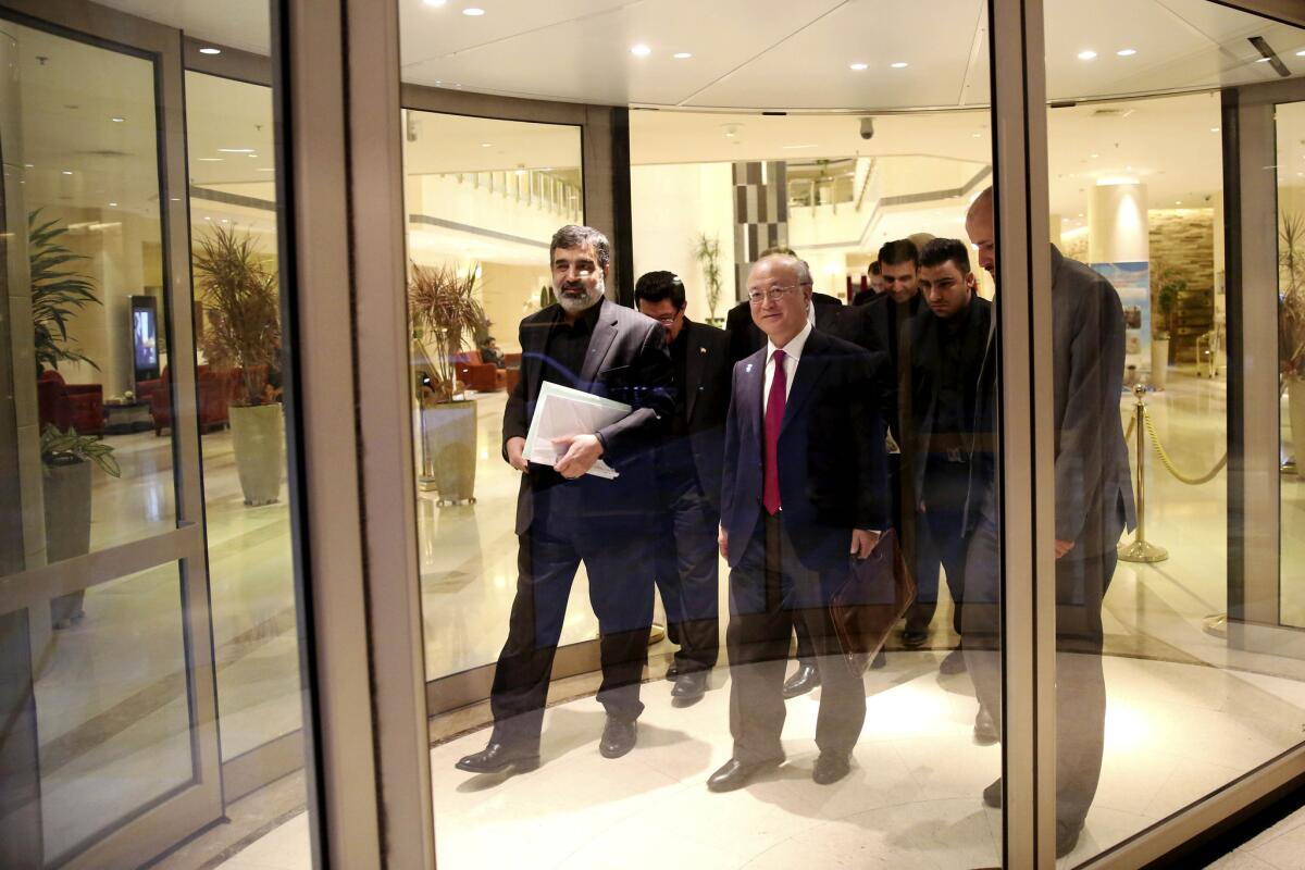 International Atomic Energy Agency Director-General Yukiya Amano, center, leaves the Azadi Hotel in Tehran after briefing reporters on the progress of nuclear negotiations with Iranian officials. Iran and the U.N. nuclear watchdog agency have reached a road map deal for cooperation that expands the monitoring of the country's nuclear sites.