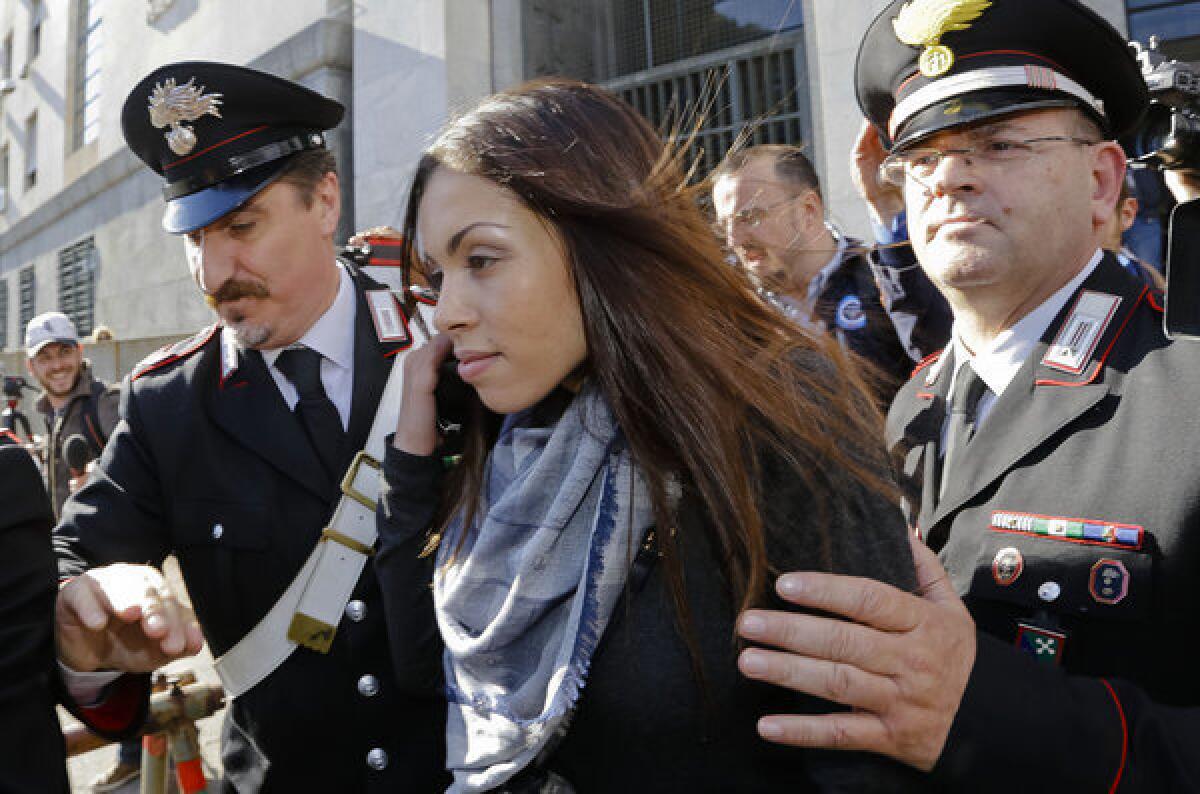 Karima el Mahroug is escorted from court in Milan after testifying in the trial of three former Silvio Berlusconi aides accused of procuring her and other women for prostitution, which she denies.